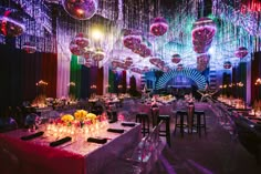 a room filled with lots of tables covered in purple and pink balloons hanging from the ceiling