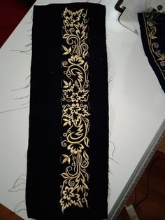 an embroidered black and gold cloth with floral design on the edge is sitting on a table