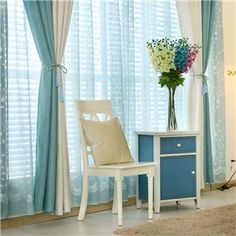 a blue and white room with flowers in a vase next to a chair on a rug