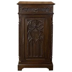 an ornate wooden cabinet with carvings on the front and side panels, in dark wood