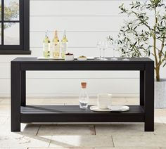 an outdoor table with drinks on it and two wine glasses sitting on the top shelf