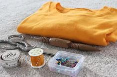 sewing supplies laid out on the floor next to a yellow blanket and scissors, thread, spools