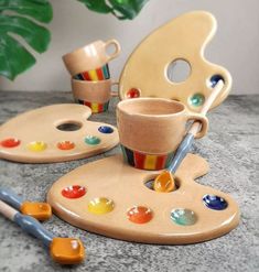 an assortment of art supplies including paintbrushes, cups and saucers on a table