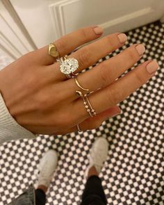 a woman's hand with four different rings on her fingers and one ring in the middle