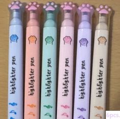 four pens with writing on them are lined up in different colors and designs, one is pink, the other is blue