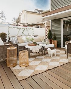 an outdoor living area with wicker furniture and rugs on the wooden flooring