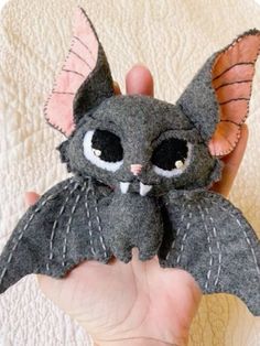 a hand holding a small stuffed animal bat