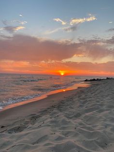 the sun is setting at the beach with waves in the water and sand on the shore