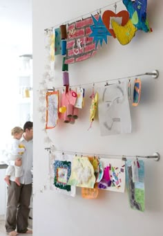 two people standing next to each other in front of a wall with pictures hanging on it