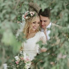 a bride and groom standing in the woods