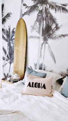 a surfboard is leaning against the wall behind a bed with white sheets and pillows