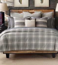 a bed with plaid comforter and pillows in a bedroom next to two pictures on the wall