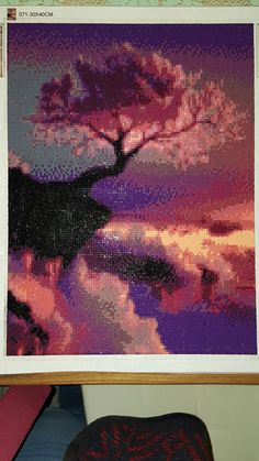 a cross - stitch picture of a tree in the middle of a painting on a wall