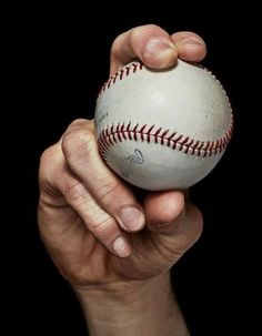 a person holding a baseball in their left hand with both hands on top of the ball