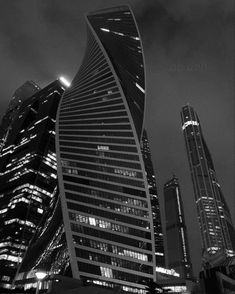 black and white photograph of skyscrapers in the city at night with lights on them