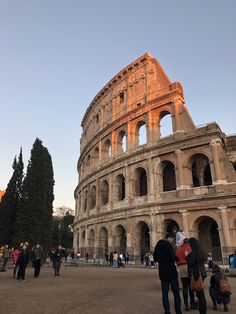 people are standing around in front of an old roman collise at sunset or sunrise