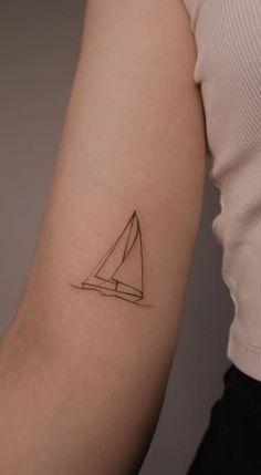 a woman's arm with a small black and white sailboat tattoo on it