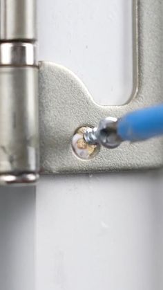 a blue toothbrush sitting on top of a white wall next to a metal object