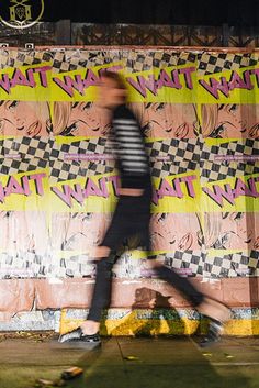 a man walking past a wall covered in graffiti