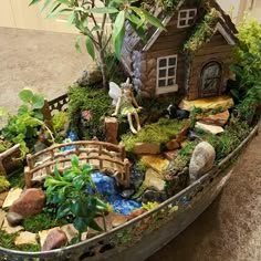 a small boat filled with lots of plants and rocks next to a house on the ground