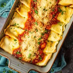 a casserole dish filled with pasta and sauce on top of a blue towel