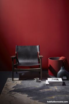 a chair and vase in front of a red wall