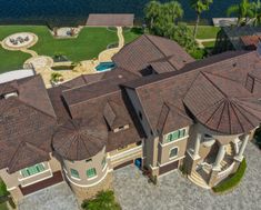 an aerial view of a large house with lots of windows and roofing in front of the water