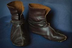 a pair of brown leather boots with laces on the sides and heel, sitting on a blue surface