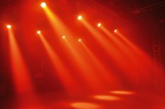 several spotlights shine brightly on a stage with red light coming from the ceiling and floor