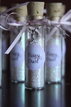 three small bottles filled with glitter and a tag that says fairy dust on the front