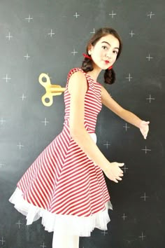 a girl in a red and white dress holding a pair of scissor scissors