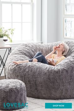 a woman laying on top of a bean bag chair next to a footstool