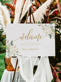 a welcome sign sitting on top of a wooden easel in front of some plants