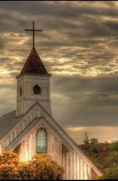 an old church with a cross on the top and clouds in the background canvas print