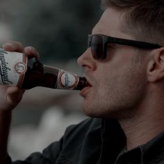 a man in sunglasses drinking from a beer bottle