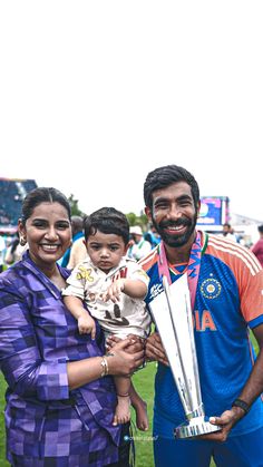 a man holding a trophy with two women and a baby in front of him at a sporting event