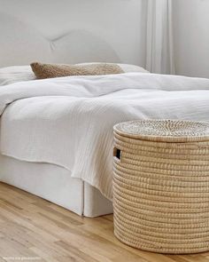 a bed with white linens and wicker baskets on the headboard