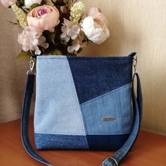 a blue purse sitting on top of a wooden table next to a bouquet of flowers