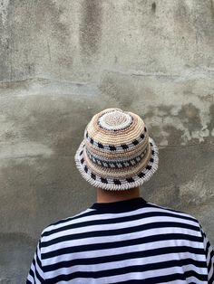 a person with a hat on their head standing in front of a wall and looking at something