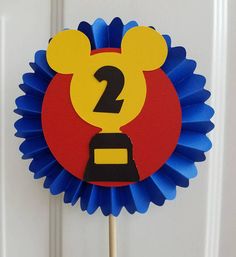 a mickey mouse cupcake topper on a stick in front of a white door