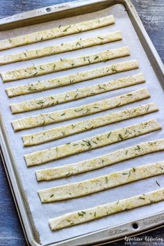 raw crackers lined up on a baking sheet ready to go into the oven with herbs