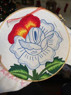 a person holding up a hand embroidered flower