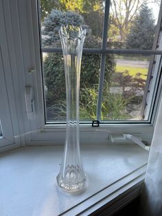 a clear glass vase sitting on top of a window sill next to a window