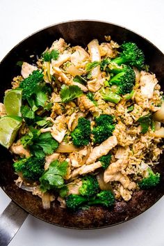 a skillet filled with chicken and broccoli on top of a white table