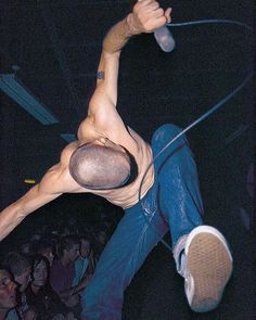 a shirtless man holding a microphone in front of a crowd