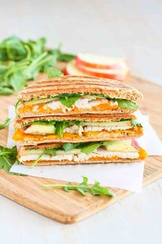 a cut in half sandwich sitting on top of a cutting board next to sliced vegetables