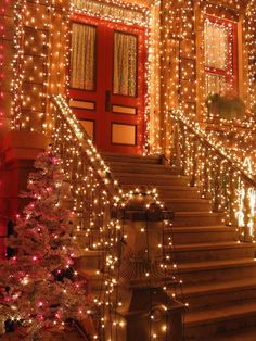 christmas lights on the side of a building with stairs leading up to it and trees in front