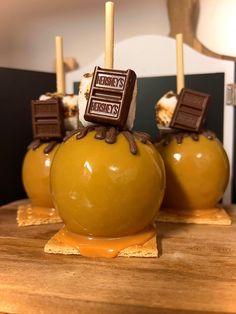 three chocolate covered apples sitting on top of a wooden table