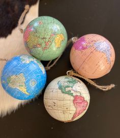 four globe ornaments are sitting on a cowhide rug, one is blue and the other is pink