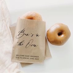 two donuts sitting on top of a brown paper bag next to a white towel